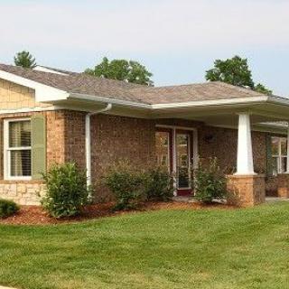 A brick house with a well-maintained front yard and landscaping.