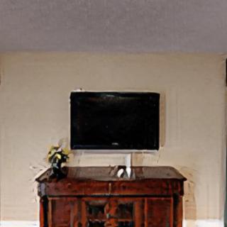 A flat-screen TV mounted on the wall above a wooden cabinet in a living room setting.