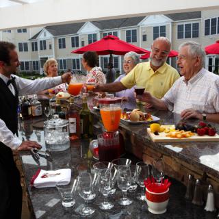 A group of people socializing at an outdoor bar, enjoying beverages and snacks.