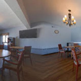 A spacious dining area featuring wooden furniture and a chandelier, set against blue walls.