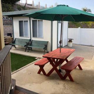 A backyard with a picnic table and umbrella, alongside a swing bench near a small garden area.