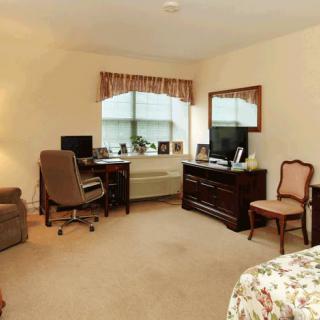 A cozy bedroom with a desk, computer, and comfortable seating.