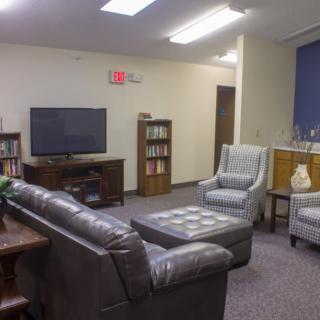 A cozy living room with sofas, armchairs, a TV, and bookshelves.