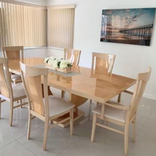 A modern dining room featuring a wooden dining table with six chairs, complemented by decorative elements and artwork on the wall.