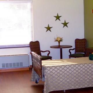 A cozy living room with two chairs and a small table, decorated with wall stars and brightened by natural light from the window.