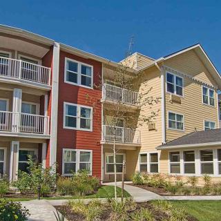 A modern apartment building with balconies and landscaped surroundings.
