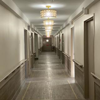 A well-lit hotel hallway featuring multiple doors and elegant ceiling lights.