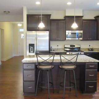 A modern kitchen featuring an island with bar stools and stainless steel appliances.