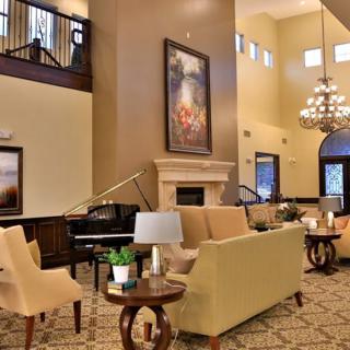 A luxurious hotel lobby featuring elegant sofas, a grand piano, and a large chandelier.