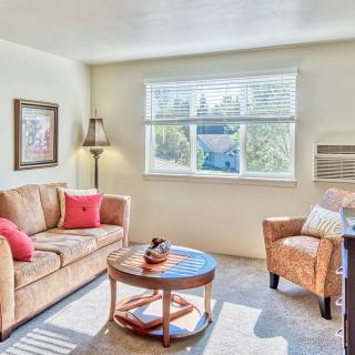 A cozy living room with a sofa, armchair, and coffee table, accented by decorative pillows and artwork.