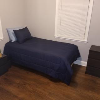 A tidy bedroom featuring a single bed with blue bedding and a nightstand beside it.