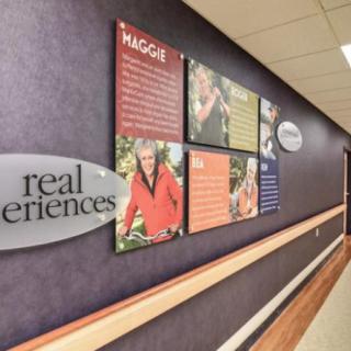 A hospital hallway featuring a wall display about real experiences with vibrant posters and images.
