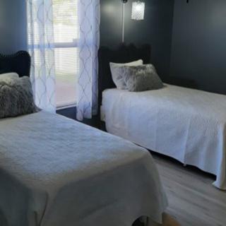 A cozy bedroom featuring two twin beds with simple white bedding and decorative pillows.