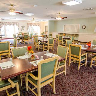 A well-organized dining room with neatly arranged tables and chairs, adorned with simple decor.