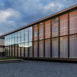 A modern building with a sleek glass facade under a partly cloudy sky.