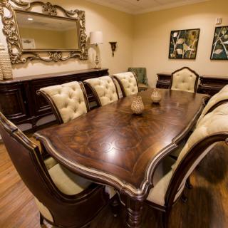 An elegant dining room featuring a large wooden table with upholstered chairs and decorative elements.