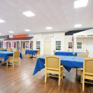 A spacious dining area featuring tables with blue tablecloths and decorative building facades.