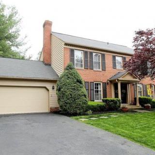 A two-story brick house with a garage and well-maintained lawn.