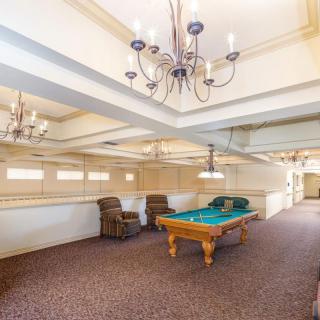 Spacious game room with a billiards table and elegant chandeliers.