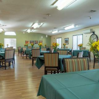 A spacious dining room with neatly arranged tables and chairs, decorated with fresh flowers.