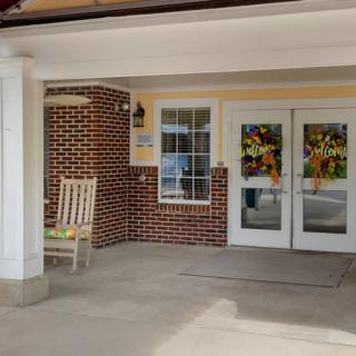 A building entrance with a rocking chair and decorated double doors.