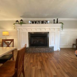 A cozy living room with a white fireplace, wooden floors, and elegant decor.