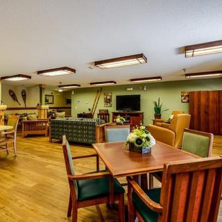 A spacious living room with wooden furniture, including tables and chairs, a television, and decorative elements on the walls.