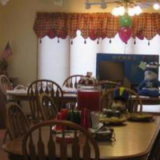 A cozy dining area with decorated tables and chairs, set for a gathering.