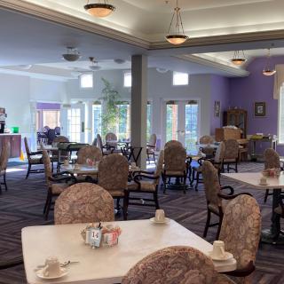 A spacious dining hall with multiple tables and chairs, featuring elegant lighting and decor.