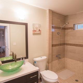 A modern bathroom featuring a glass bowl sink, tiled shower area, and contemporary fixtures.