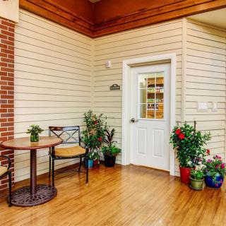 A cozy indoor space featuring a table and chairs, surrounded by vibrant plants and a door leading to another room.