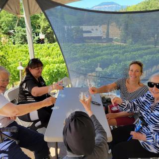 A group of people enjoying a celebratory toast outdoors under a tent with a scenic background.