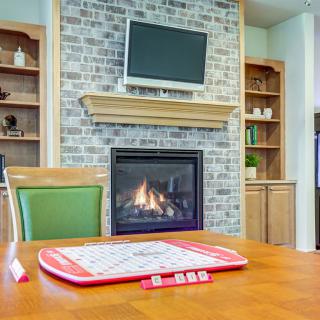 A cozy living room with a fireplace, brick wall, and a board game set up on the table.