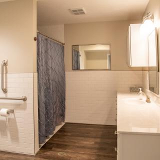 A modern bathroom with a shower, mirror, and double sink.