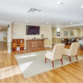 A spacious room with hardwood floors, featuring comfortable chairs and a mounted television.