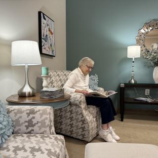 An elderly person reading a magazine in a cozy living room setting.