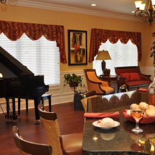 A stylish living room featuring a grand piano, elegant furniture, and warm lighting.