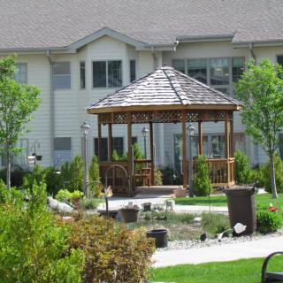 A well-maintained garden featuring a wooden gazebo in front of a residential building.