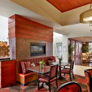 A modern hotel lobby featuring a cozy seating area with a fireplace, accented by contemporary decor and comfortable furniture.