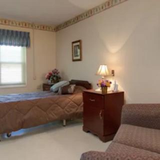 A cozy bedroom with a single bed, decorated with a lamp, side table, and window.