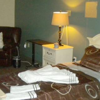 A cozy bedroom with a bed, a lamp on the nightstand, and a leather chair.