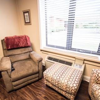A cozy corner featuring a recliner and an ottoman by the window.