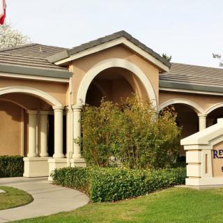 A house with classical architecture, featuring columns and a well-maintained garden.