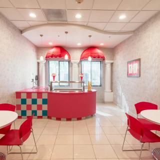 A brightly decorated ice cream parlor with red and white colors, featuring a seating area and counter.