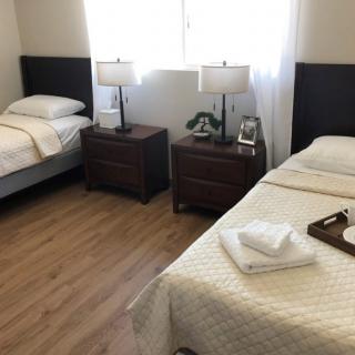 A tidy bedroom with two twin beds, nightstands, and a window.