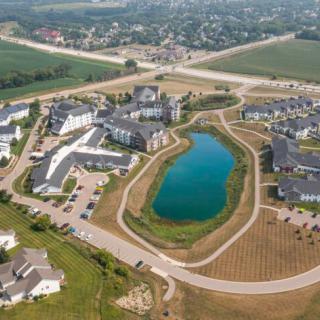 Aerial view of a residential housing development with a central lake and surrounding roads.
