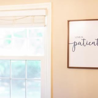 A cozy room featuring a window with soft lighting and a framed inspirational quote on the wall.