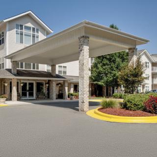 A modern building entrance with a covered driveway and landscaped surroundings.