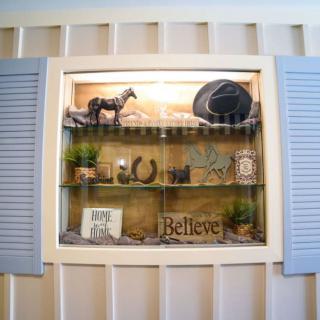 A decorative shelf display featuring a horse figurine, hat, plants, and inspirational signs.