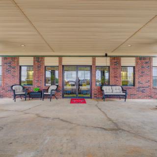 A covered entryway with outdoor seating in front of a brick building.